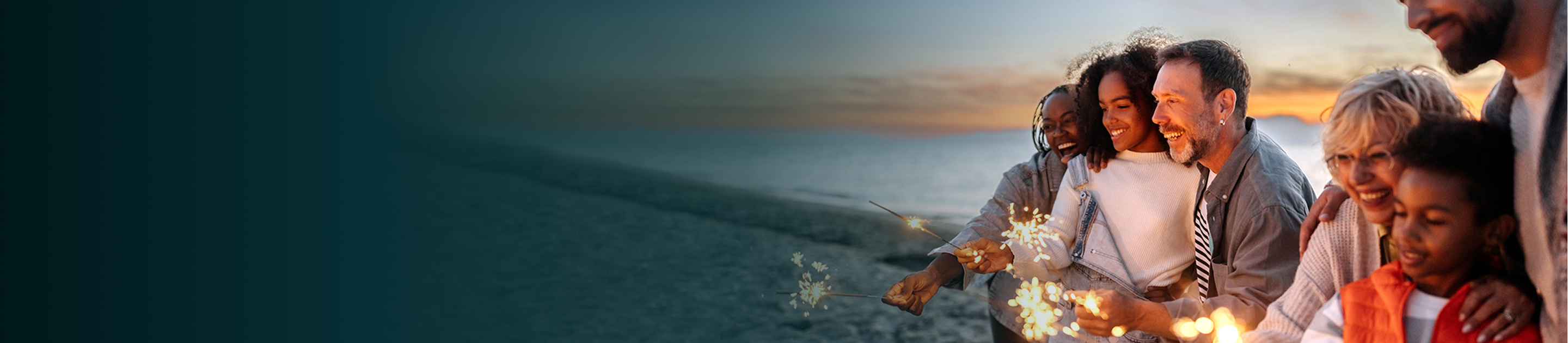 A multigenerational family playing with sparklers on the beach.