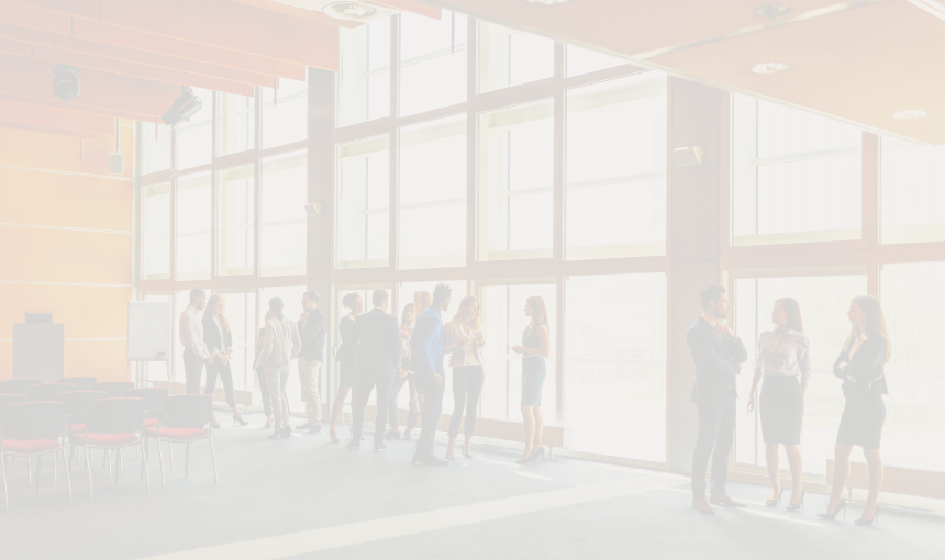 A small crowd of business professionals conversing in a conference room.