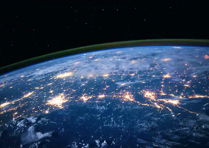 Earth from space at night with city lights glowing across continents.