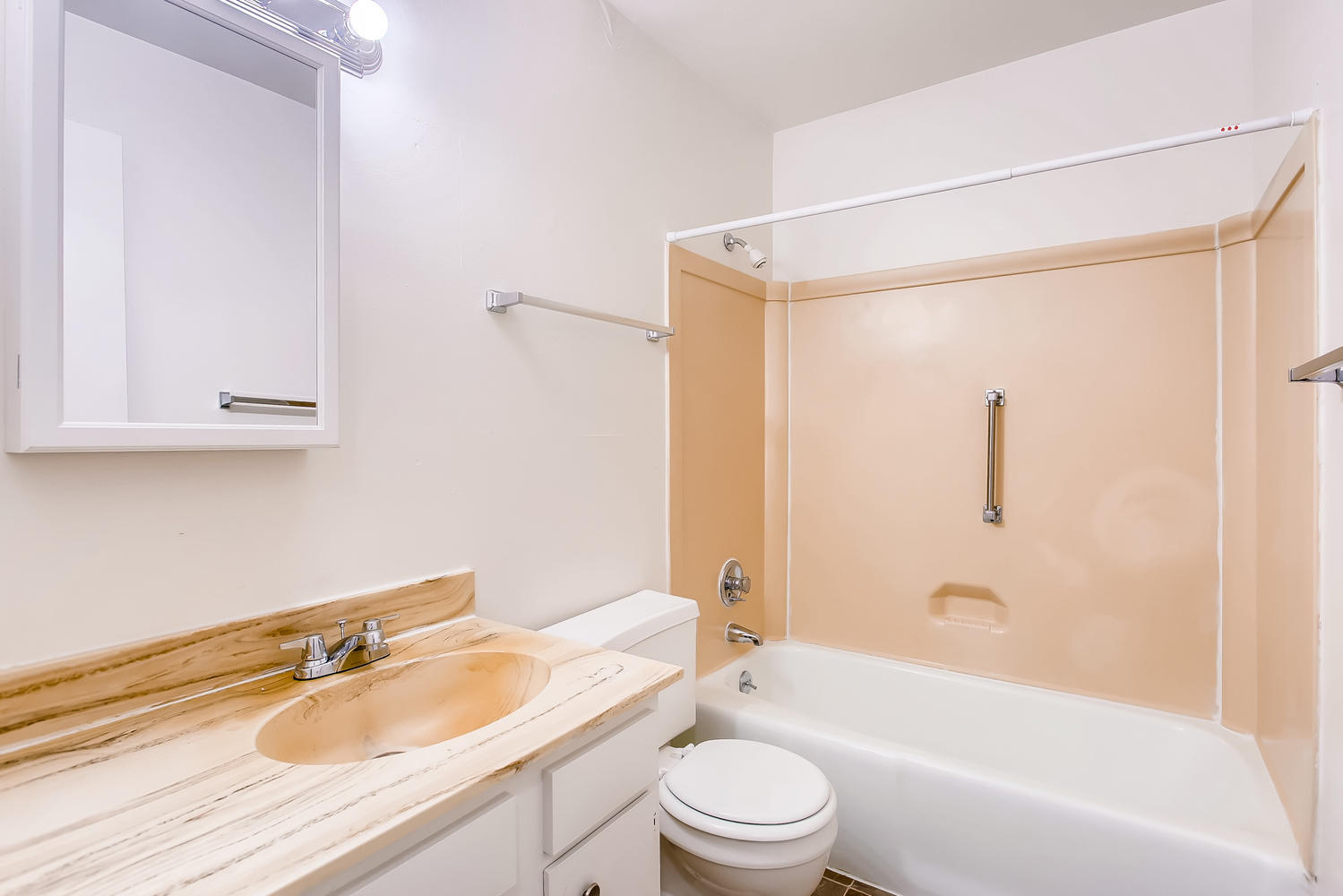 Bathroom with midcentury-inspired pink-tone counter and shower, plus mirror medicine cabinet.