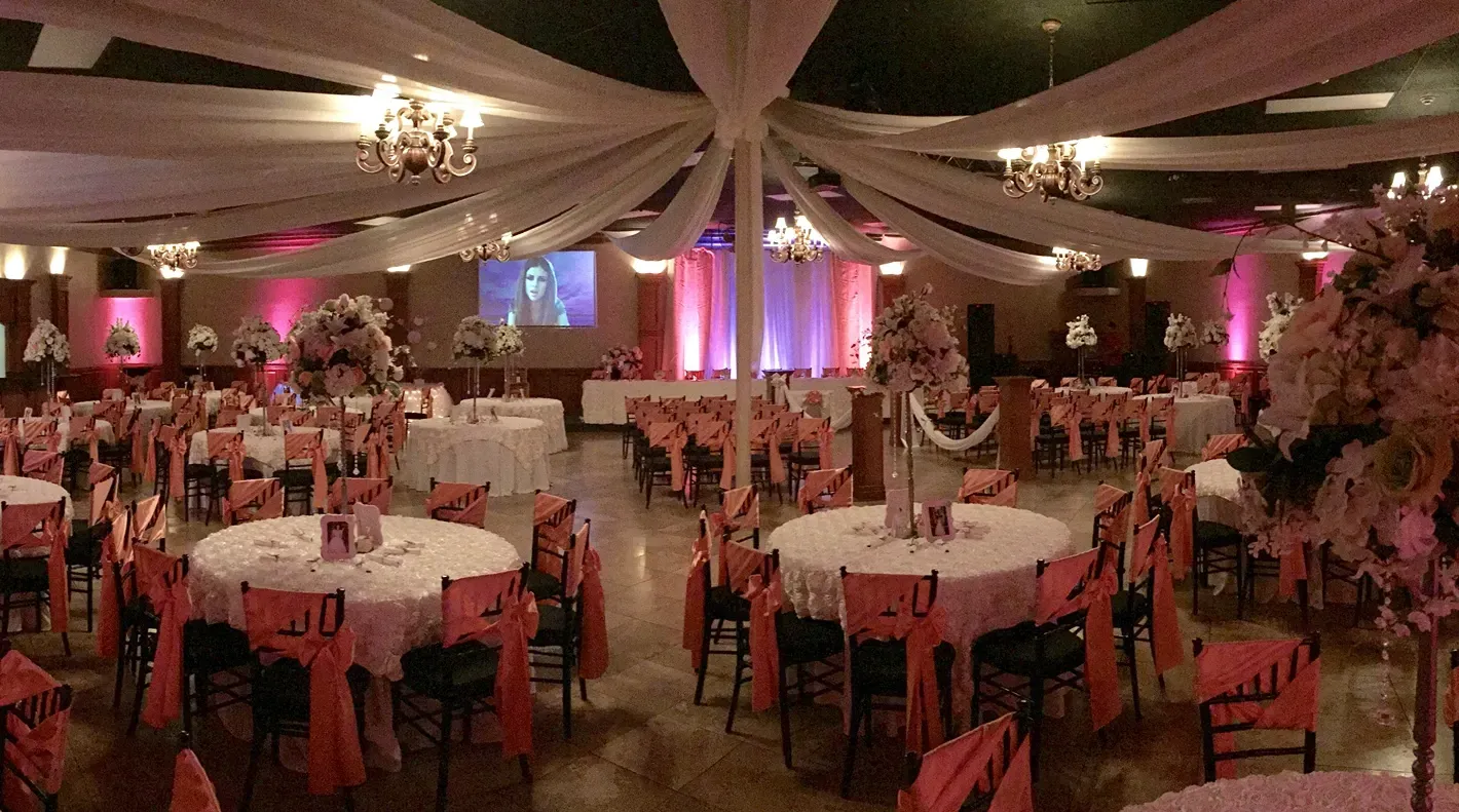 Stylish banquet hall showcasing pink uplighting, elegant table arrangements, floral centerpieces, ce 