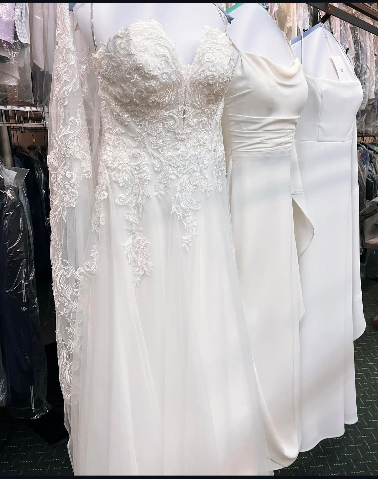 A close-up view of intricately embroidered white and ivory wedding gowns hanging on display racks after expert care at Plaza Cleaners.