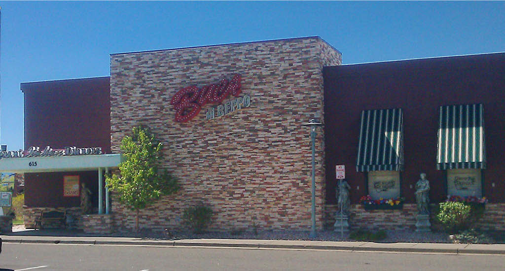 White brick and red restaurant with green and white striped window accents at Buca di Beppo Broomfield.