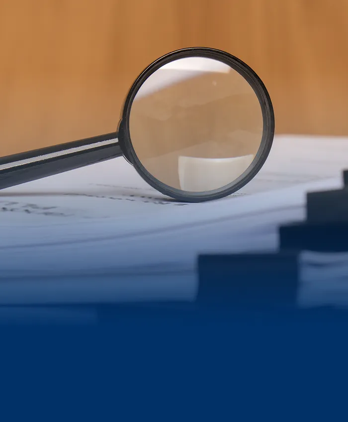 A magnifying glass sitting upright on a stack of papers.