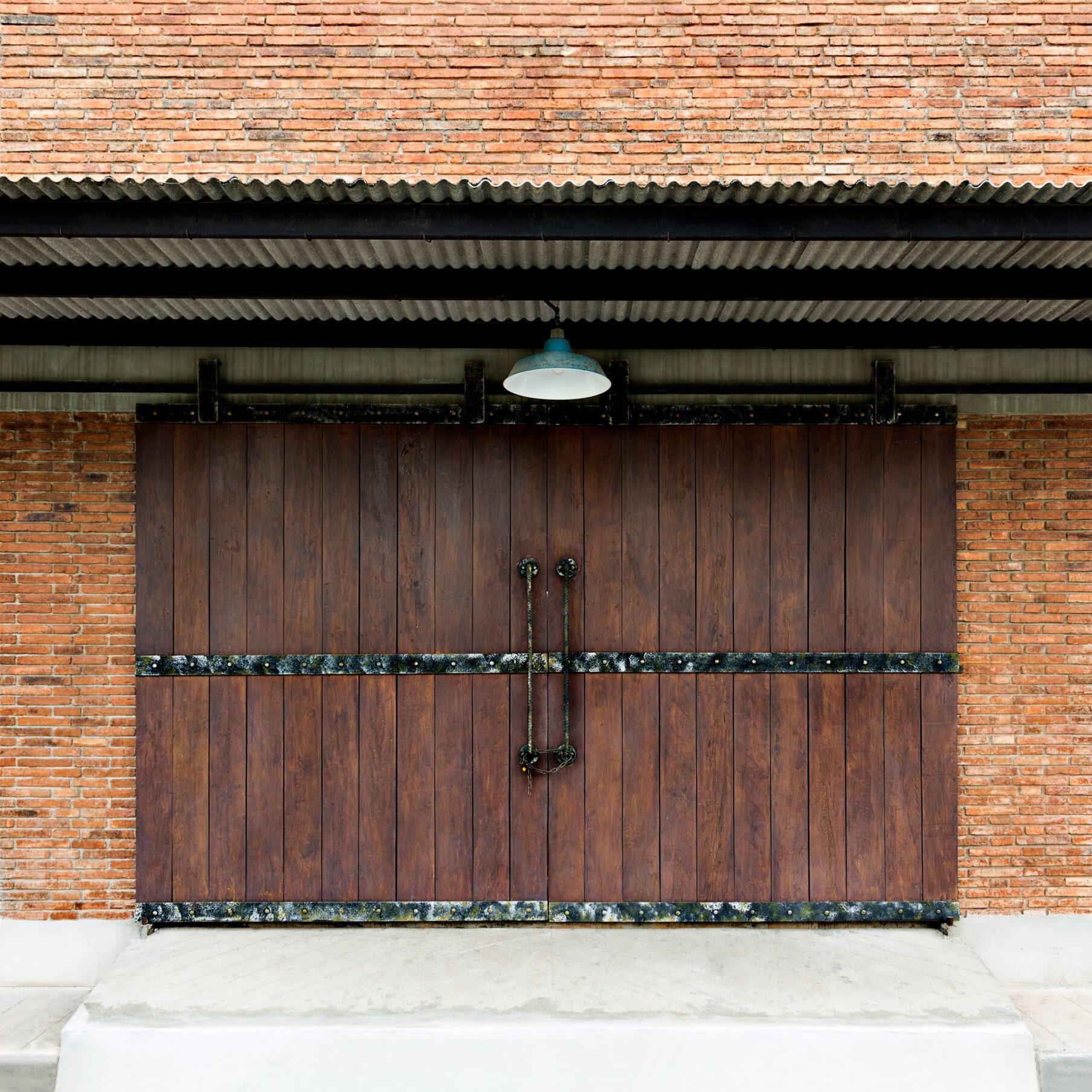 "Old wooden door texture plank in a wall traditional brickwork exterior of building with roof."