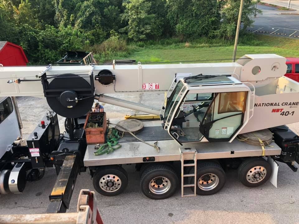 Large mobile crane truck parked outdoors with extended boom, operator cab, and equipment compartments visible, showcasing heavy-duty machinery used for lifting, construction, and industrial service operations in professional work environment.
