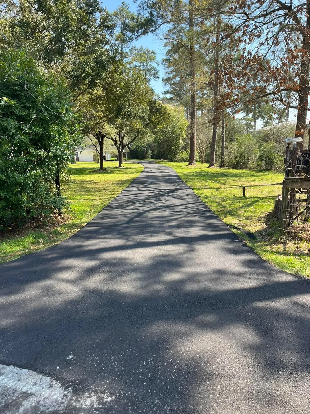 Professionally installed asphalt driveway with smooth curves, clean finish, and landscaped surroundings enhancing residential property access and appearance.