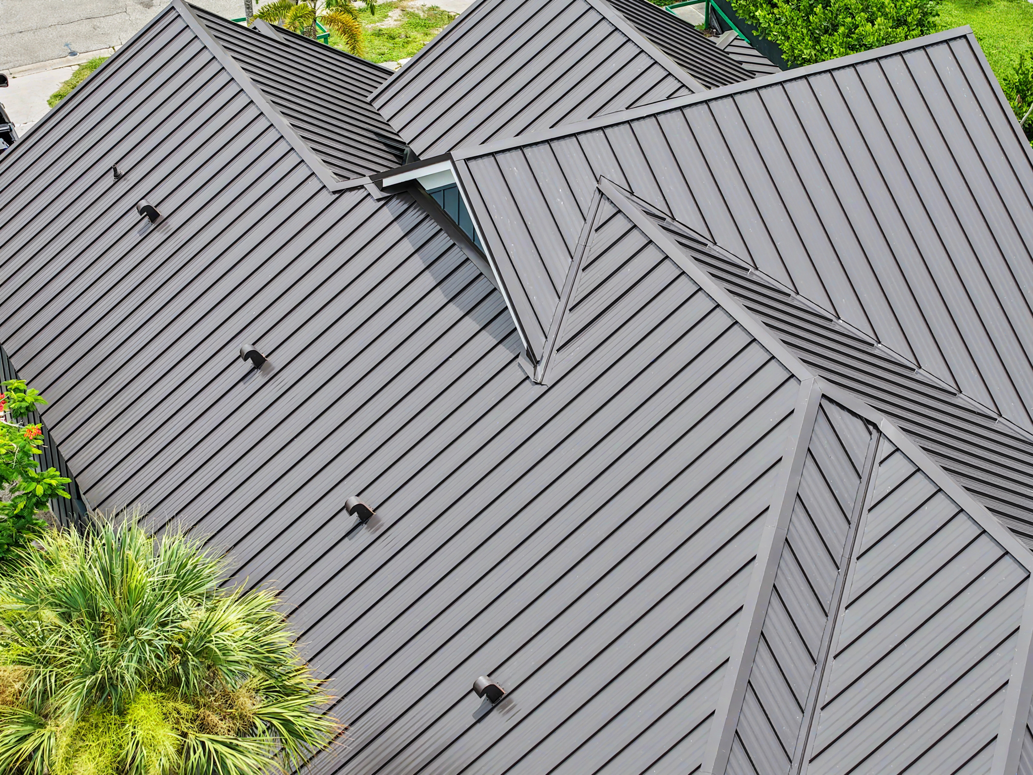 Close aerial view of a dark standing seam metal roof highlighting the clean panel lines, ridges, val 