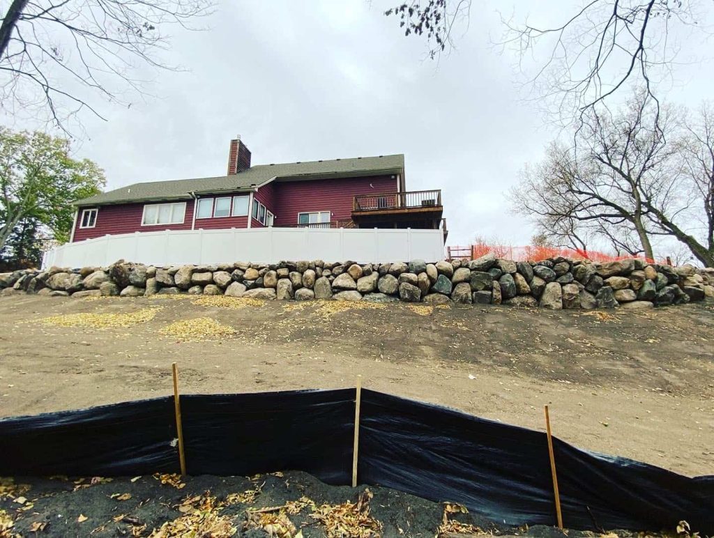A natural boulder retaining wall paired with erosion control fabric, built to hold your landscape in place for years to come.