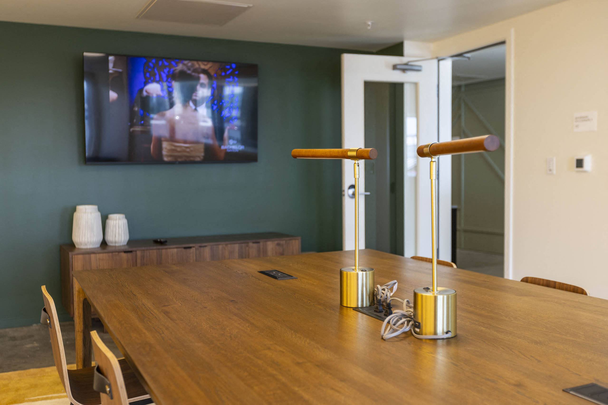 a dining room with a wooden table and a tv on the wall