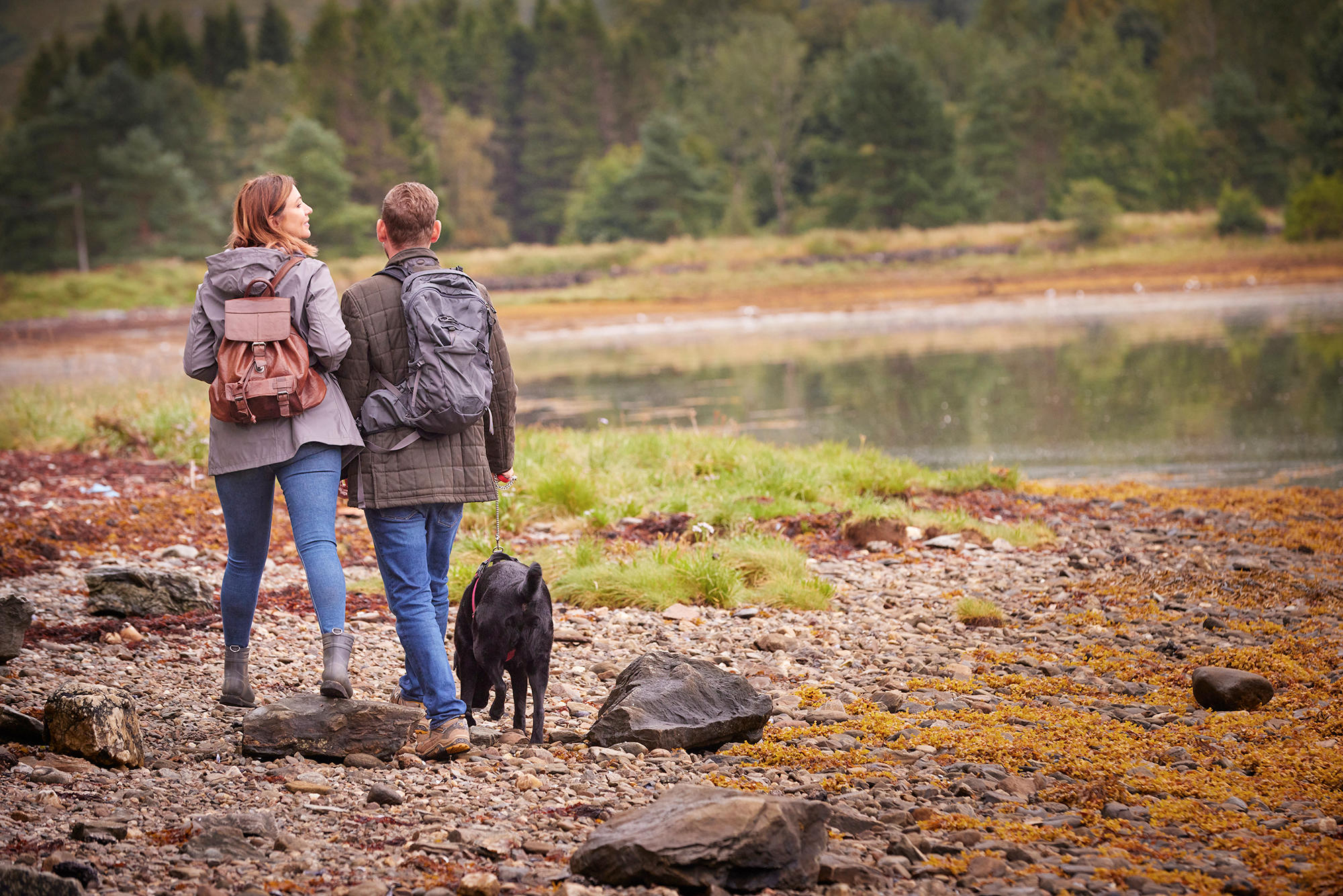 Couple stroll with their dog through the grounds of Drimsynie Estate
