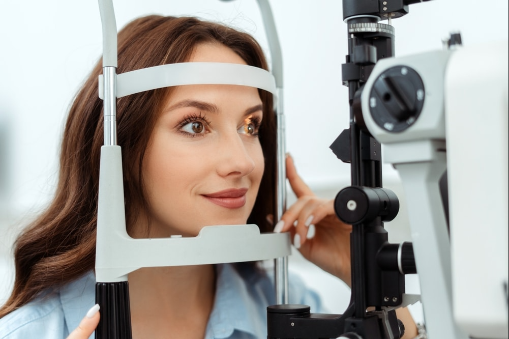 Woman receiving an eye exam through a slit lamp