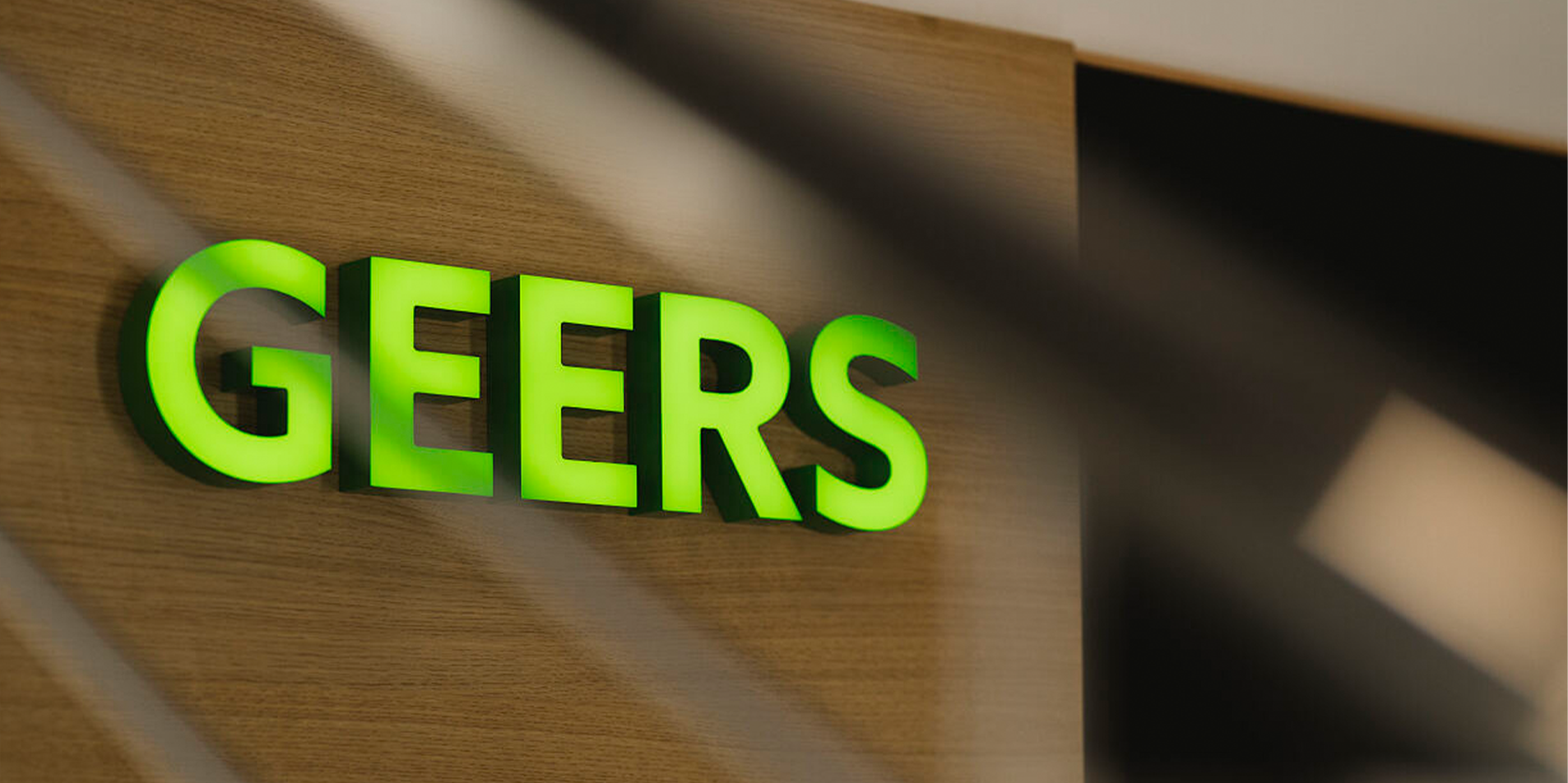 grünes GEERS Logo auf braunem Hintergrund