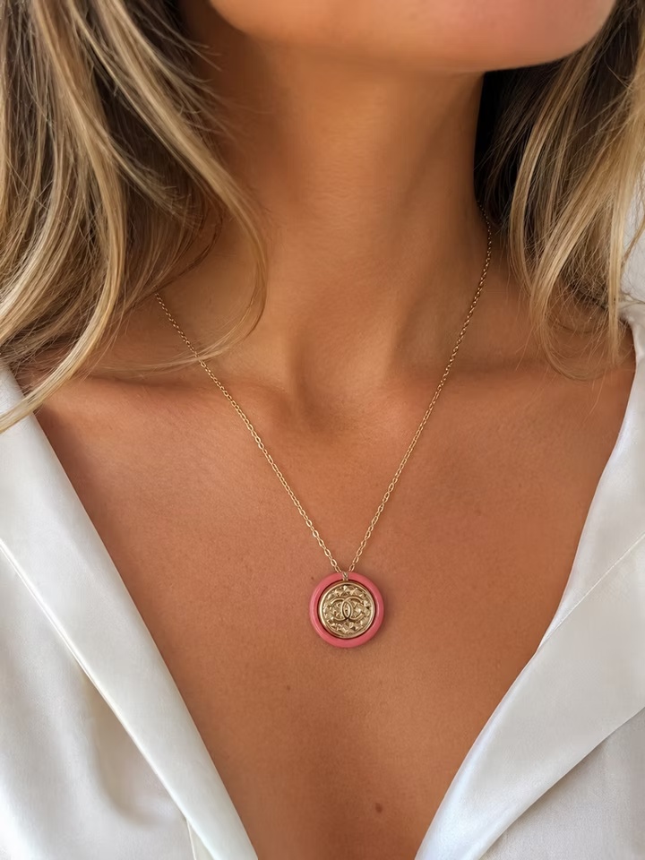 Close-up of the Rose Lumière Pendant Necklace worn on a model, featuring a delicate gold chain and a circular pendant with a gold-tone center and soft pink enamel border.