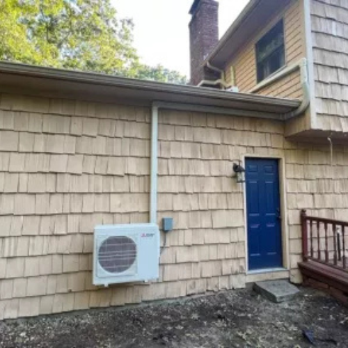 A Mitsubishi heat pump installed off the ground outside of a residential home by National Refrigeration