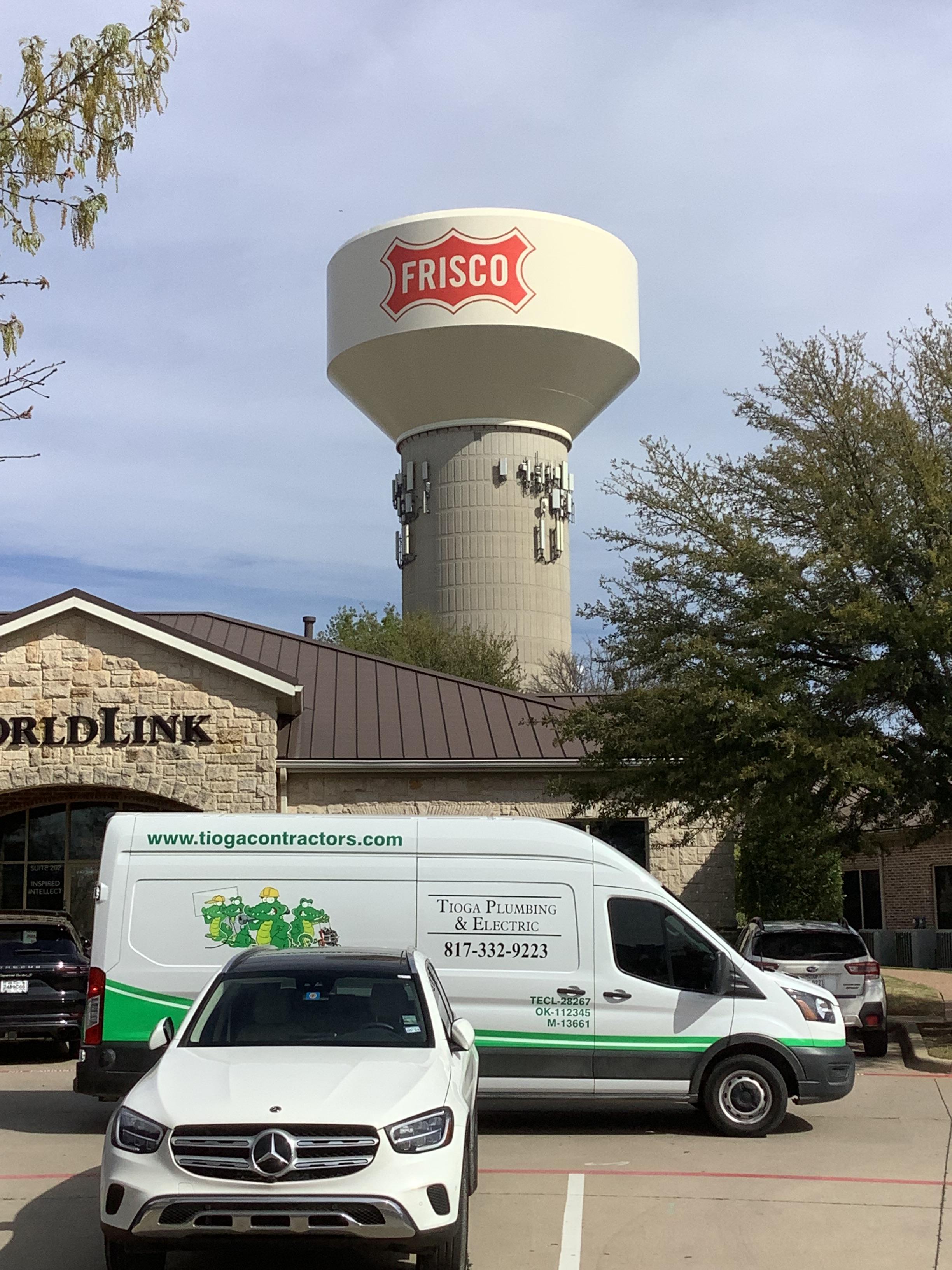 One of the Tioga Plumbing & Electric vans in front of WorldLink and a water tower in Frisco Texas.