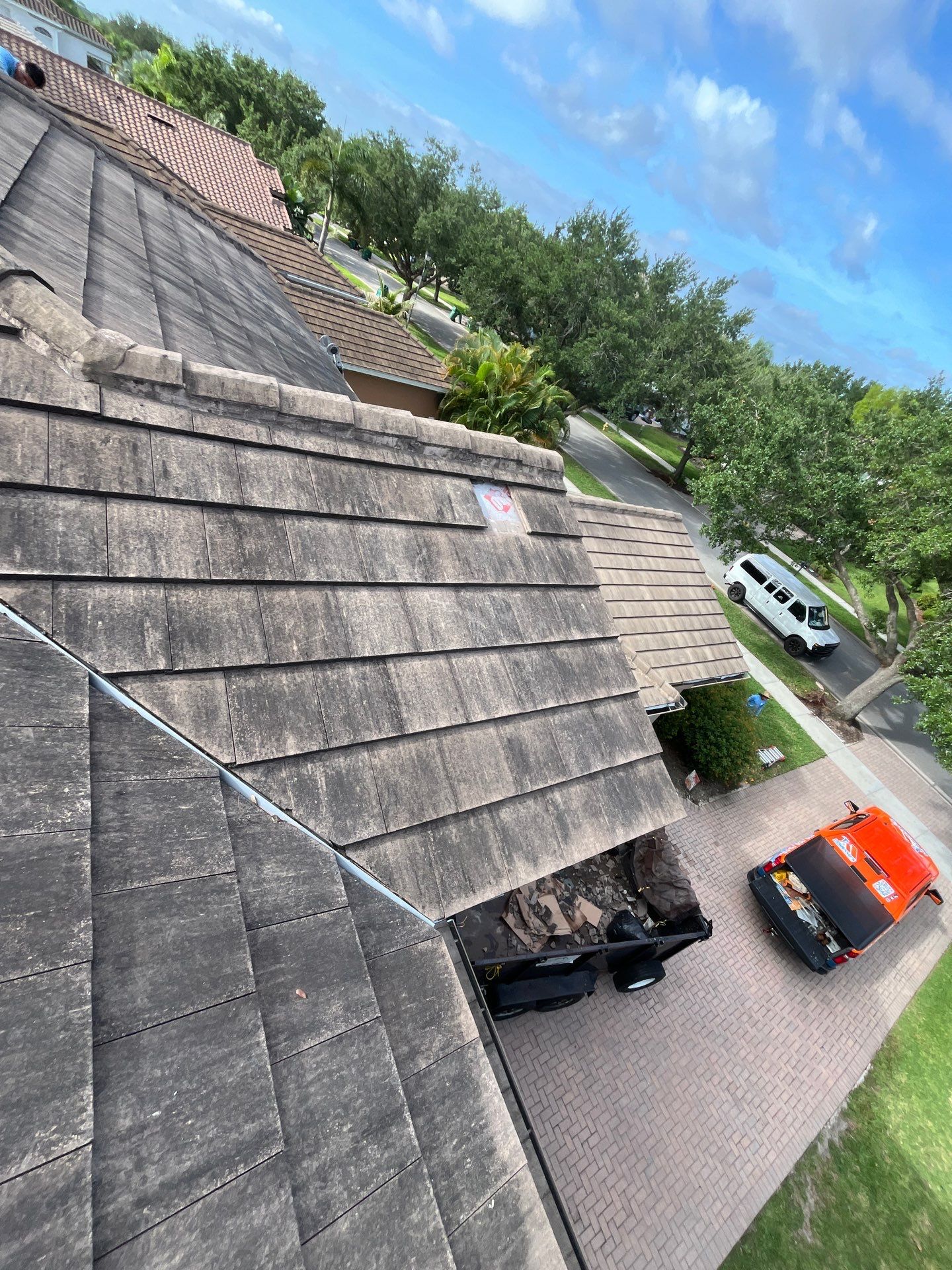 Wide view of a residential roof with underlayment installed across multiple slopes, showing active r 