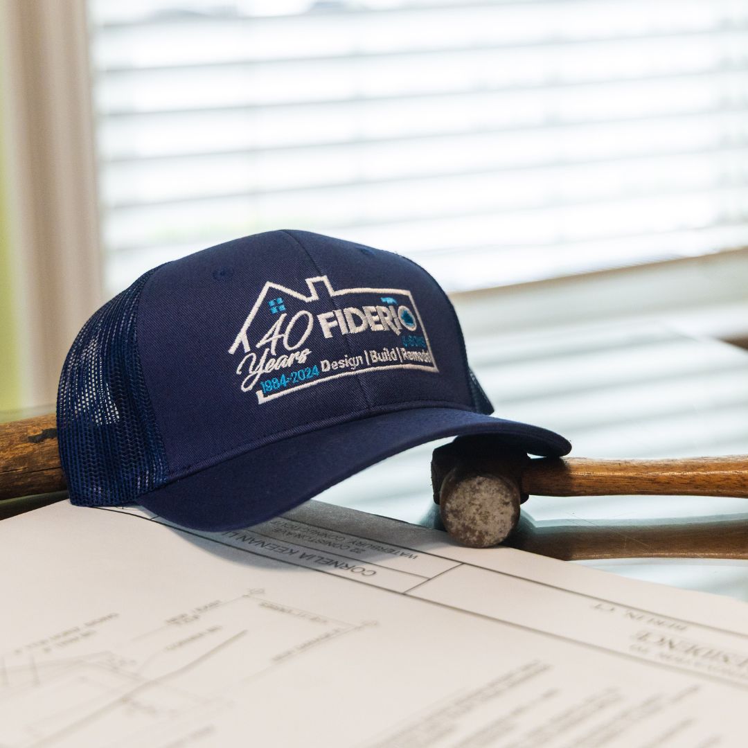 Fiderio & Sons’ 40th anniversary hat resting on architectural plans and a classic wooden hammer.