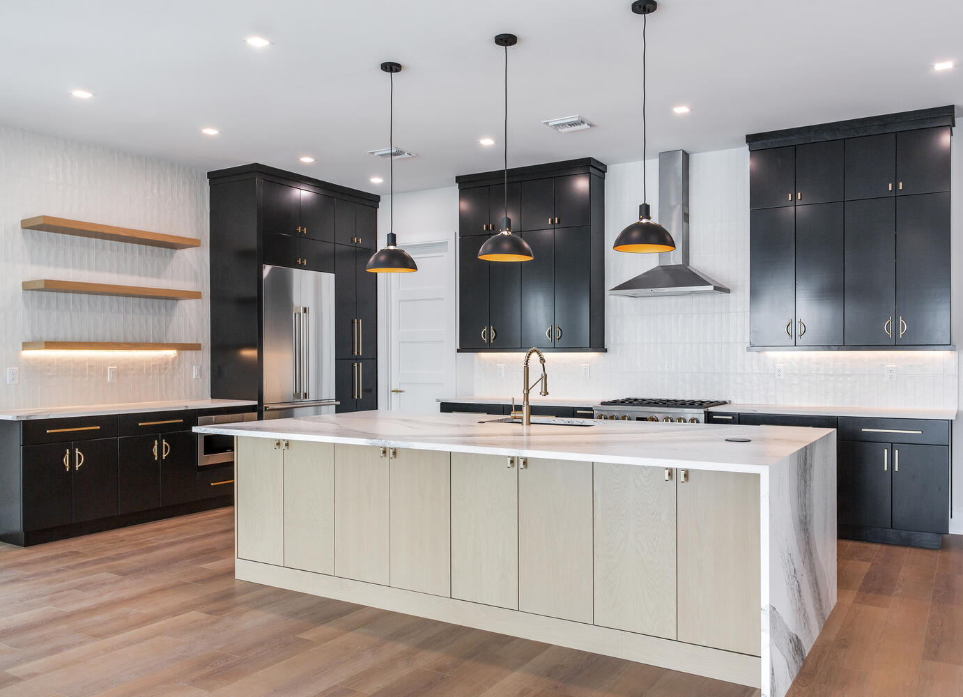 Luxury AVENTIS custom kitchen featuring a large waterfall island, dark cabinetry, pendant lighting, premium appliances, and modern coastal-inspired finishes.