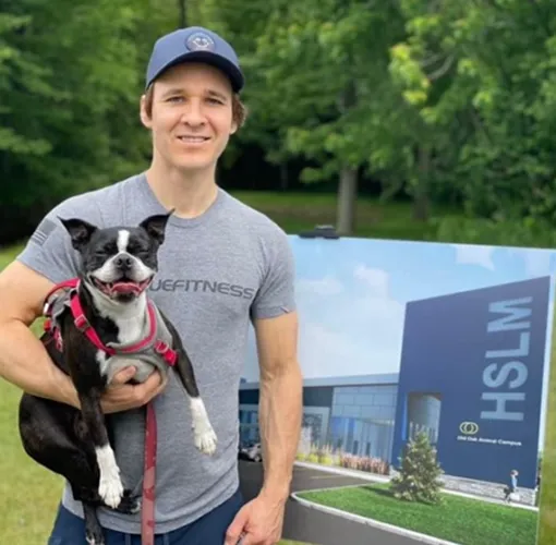 A volunteer holding a small dog in front of a Humane Society London and Middlesex banner.