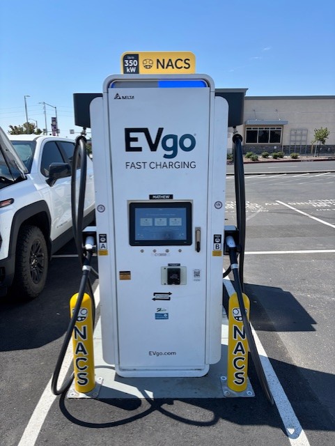 NACS EVgo fast charging unit installed in marked parking space at a public charging station, with EV 
