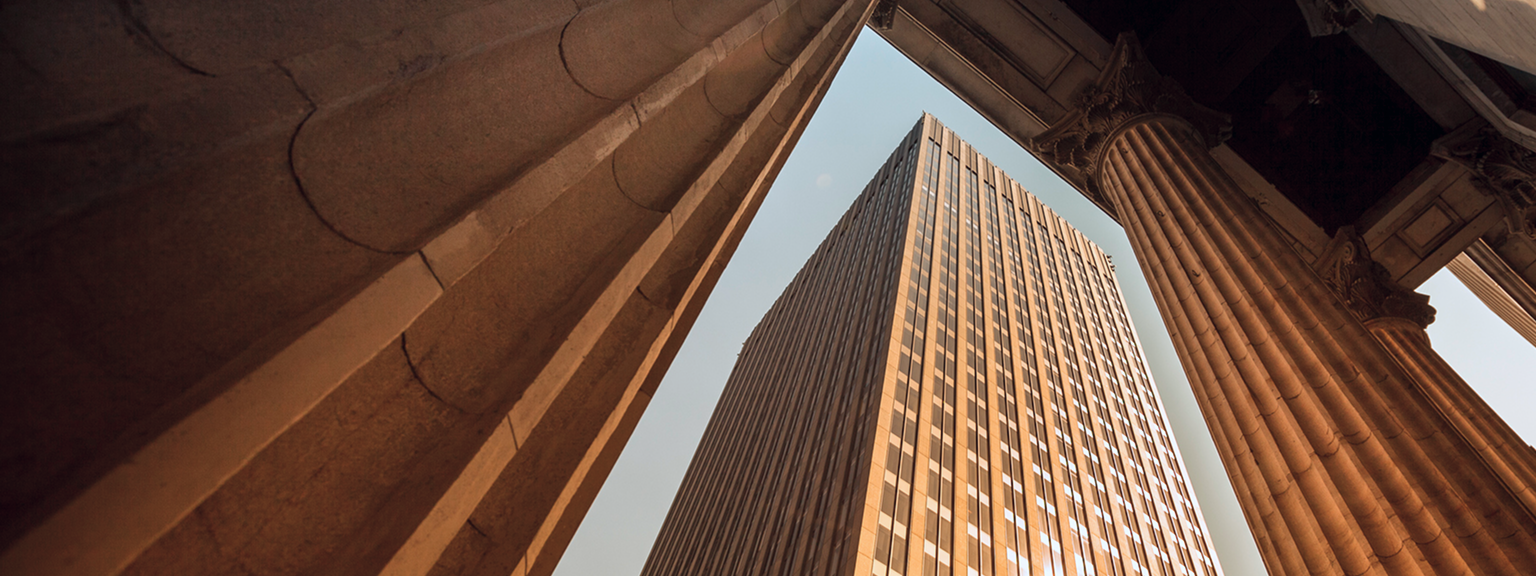 Bottom-up view of a skyscraper and classical columns.