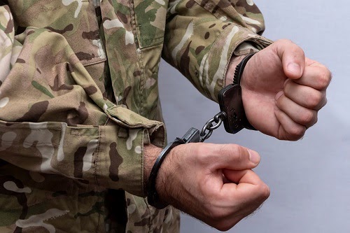 The image shows a close-up view of a person's hands secured with handcuffs.