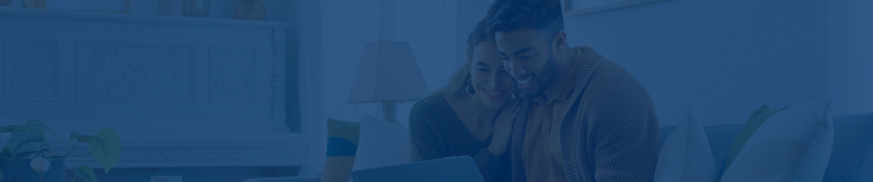 A couple on the couch looking at their iPad.