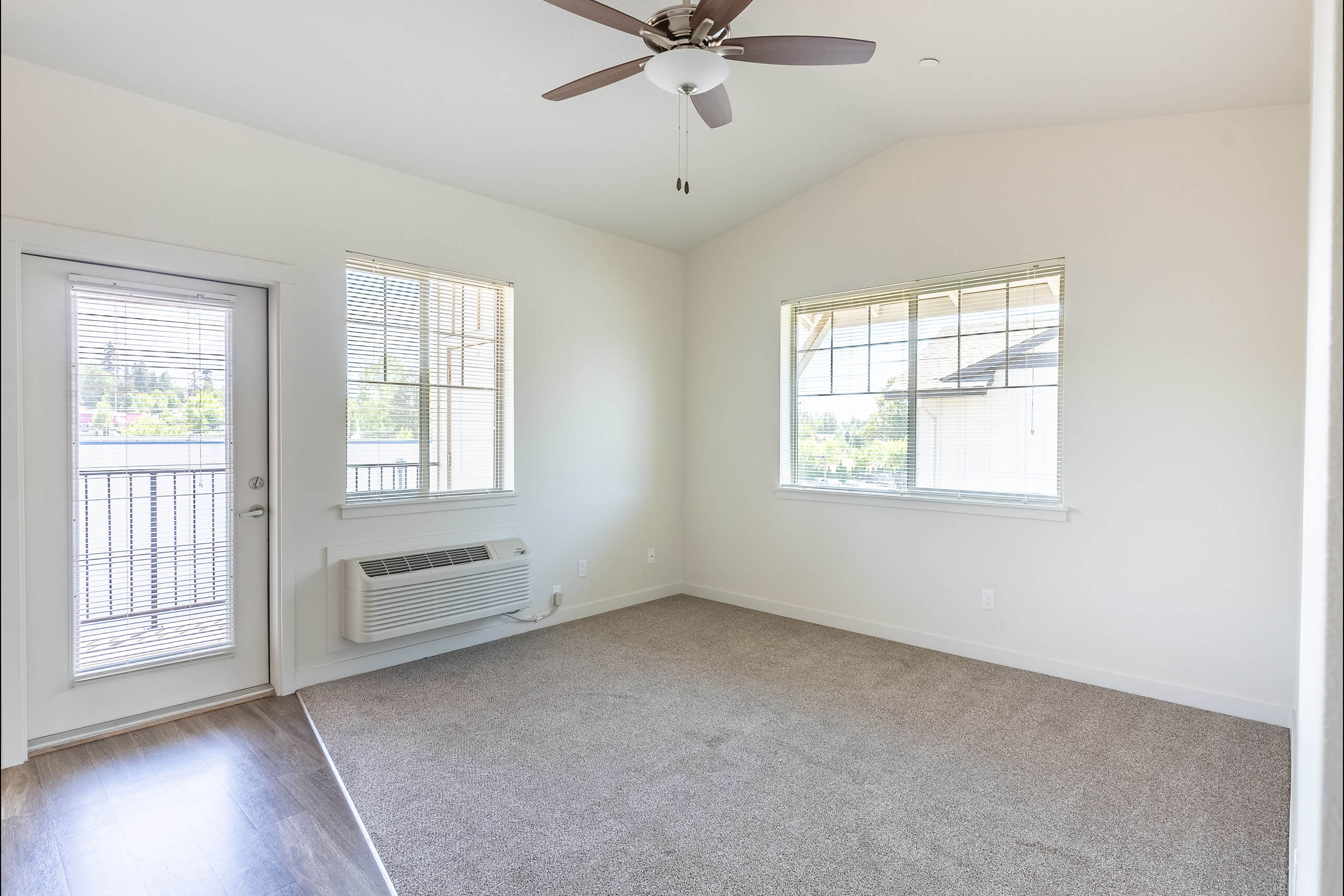 A room with a ceiling fan and two windows.