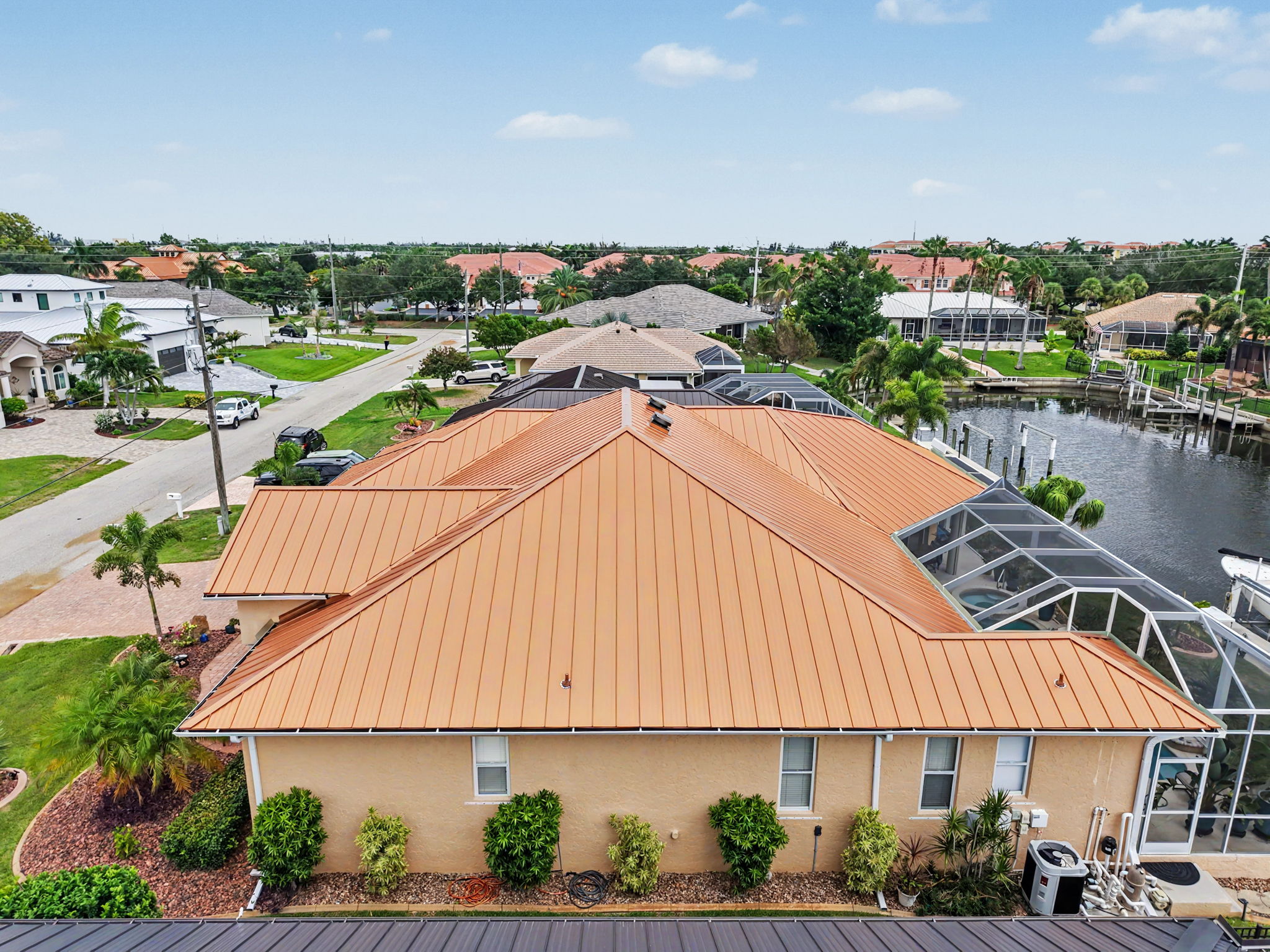 Elevated rear view highlighting the copper metal roofing system, screened pool enclosure, and surrou 