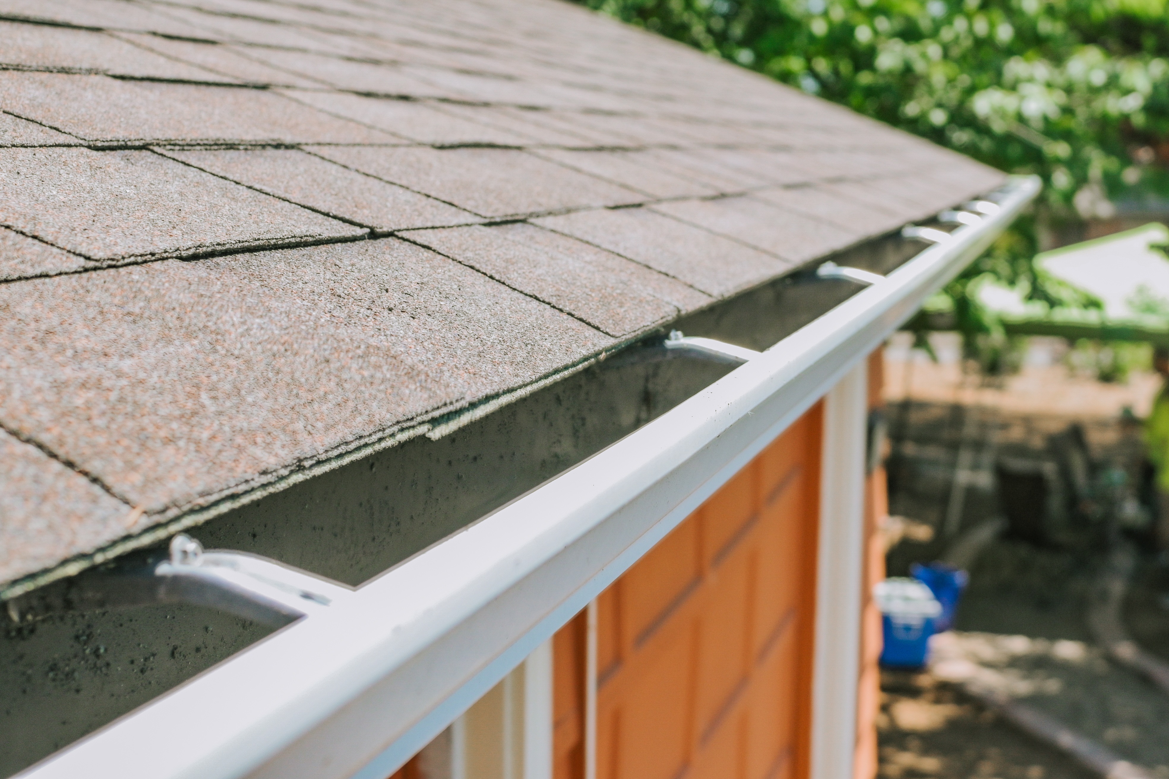 Close-up of the roof edge, asphalt shingles, and gutter system on a residential home. 