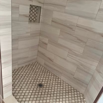 Custom tiled shower wall with a decorative mosaic accent band. 
