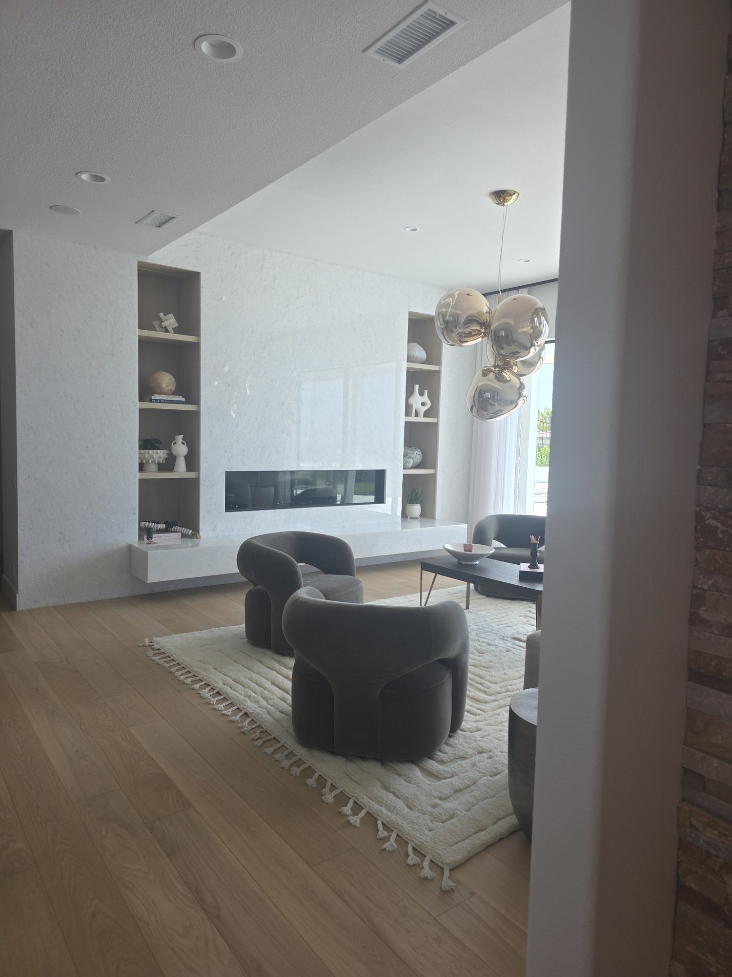 Open-concept living area with hardwood flooring, custom feature wall, and built-in shelving. 