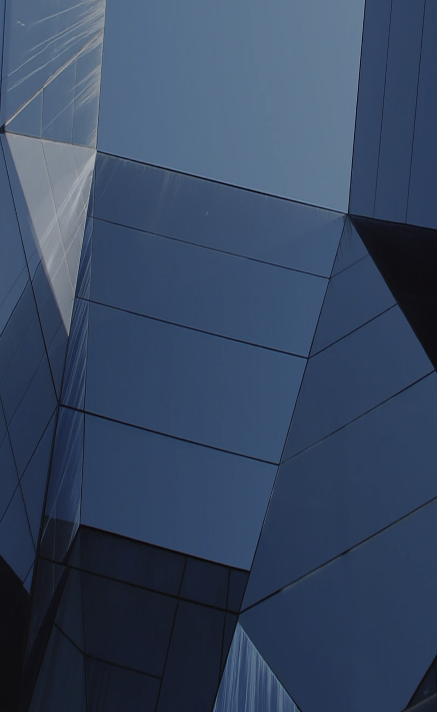 Close-up and abstract image of a modern, angular, glass-faced building.