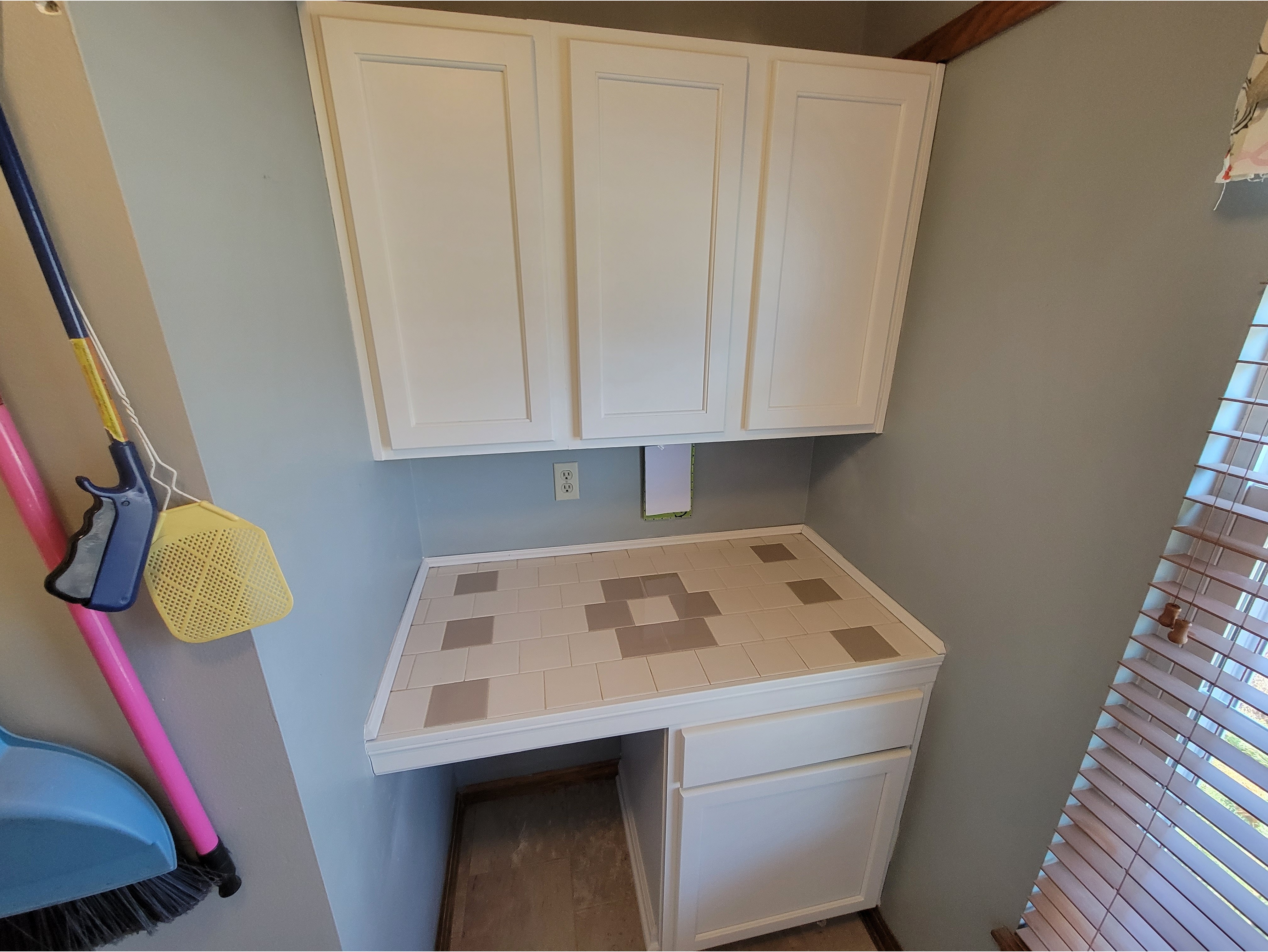 A laundry room workspace featuring freshly painted white cabinets with a smooth, clean finish and matching lower cabinetry for added storage. Ideal for showcasing cabinet painting and refinishing services that provide a modern, updated look while enhancing functionality.