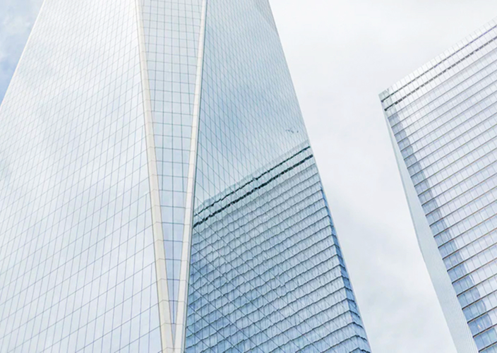 Modern glass skyscrapers against a grey, cloudy sky.