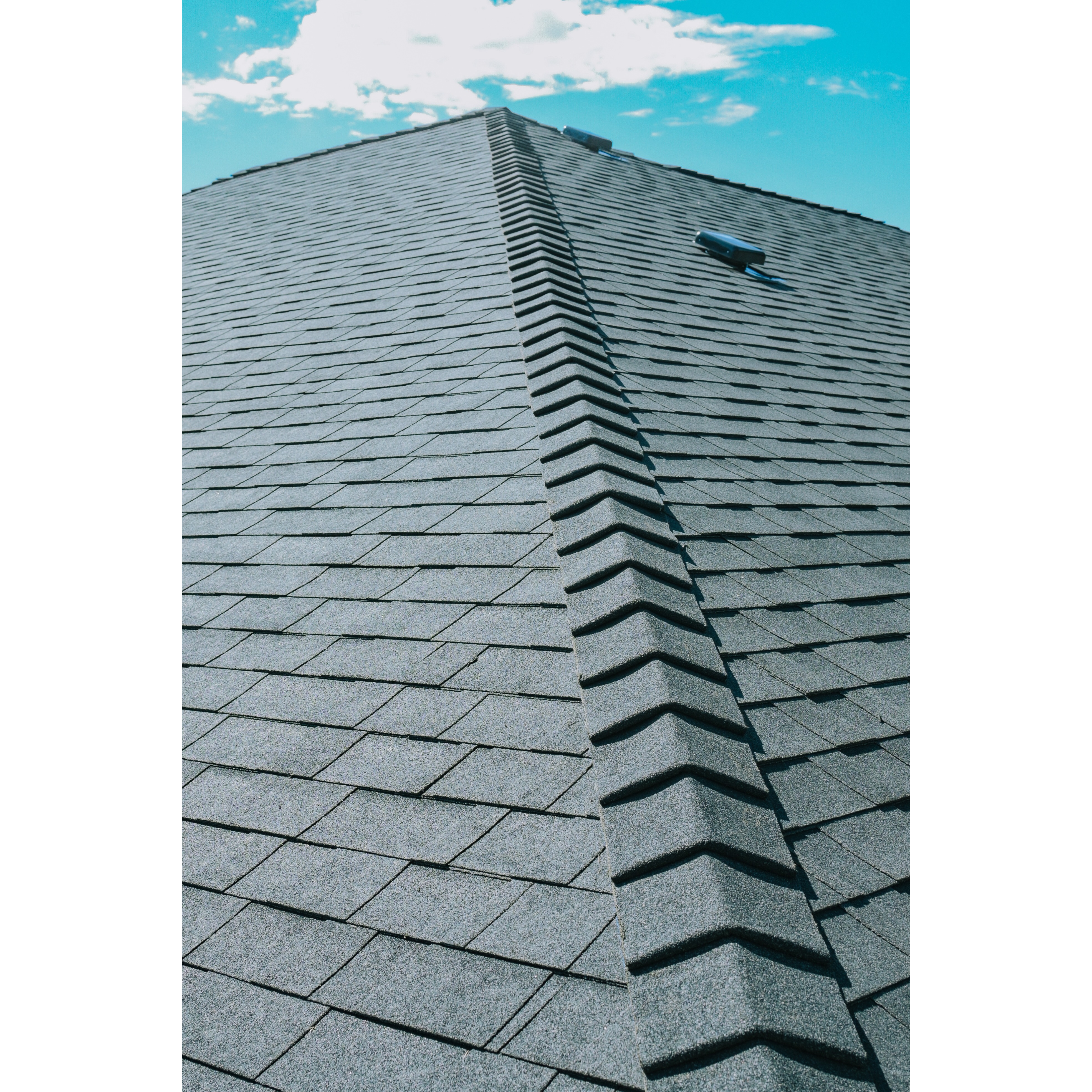 Close-up of a finished asphalt shingle roof hip with consistent ridge-cap installation. 