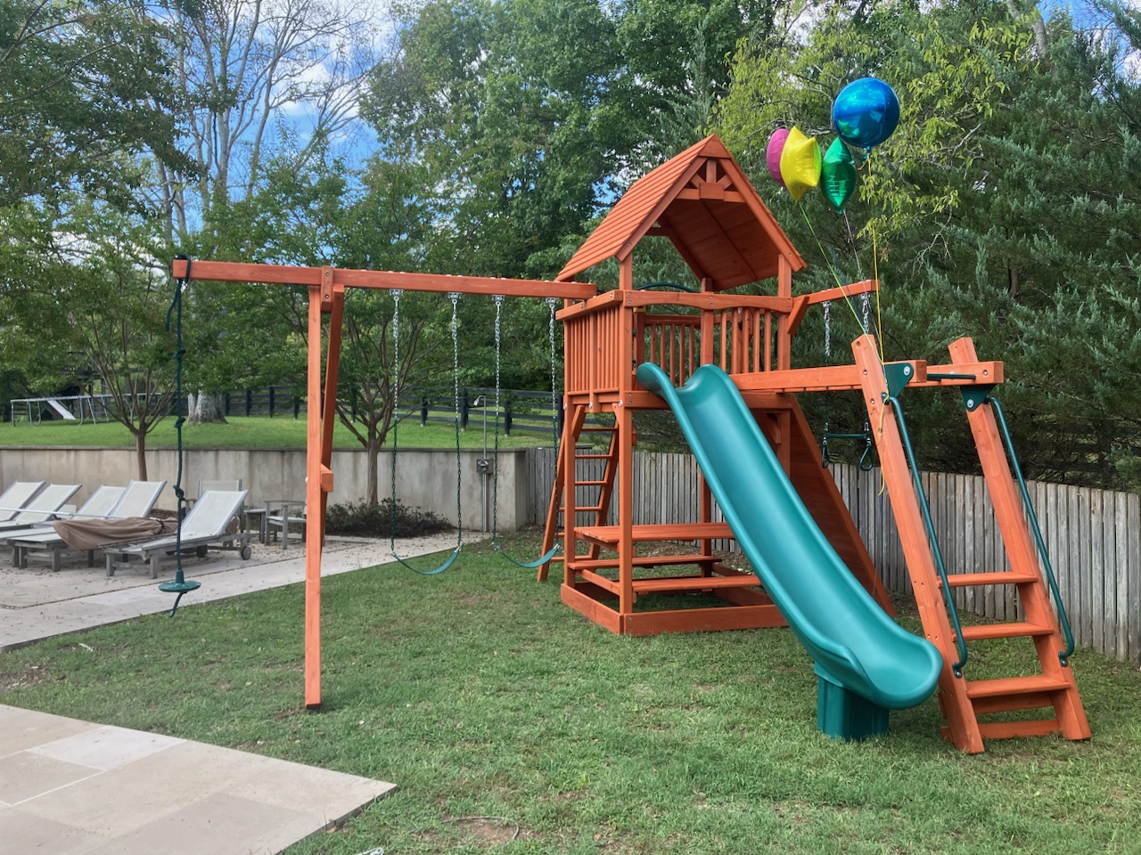 Residential wooden playset with green wave slide.