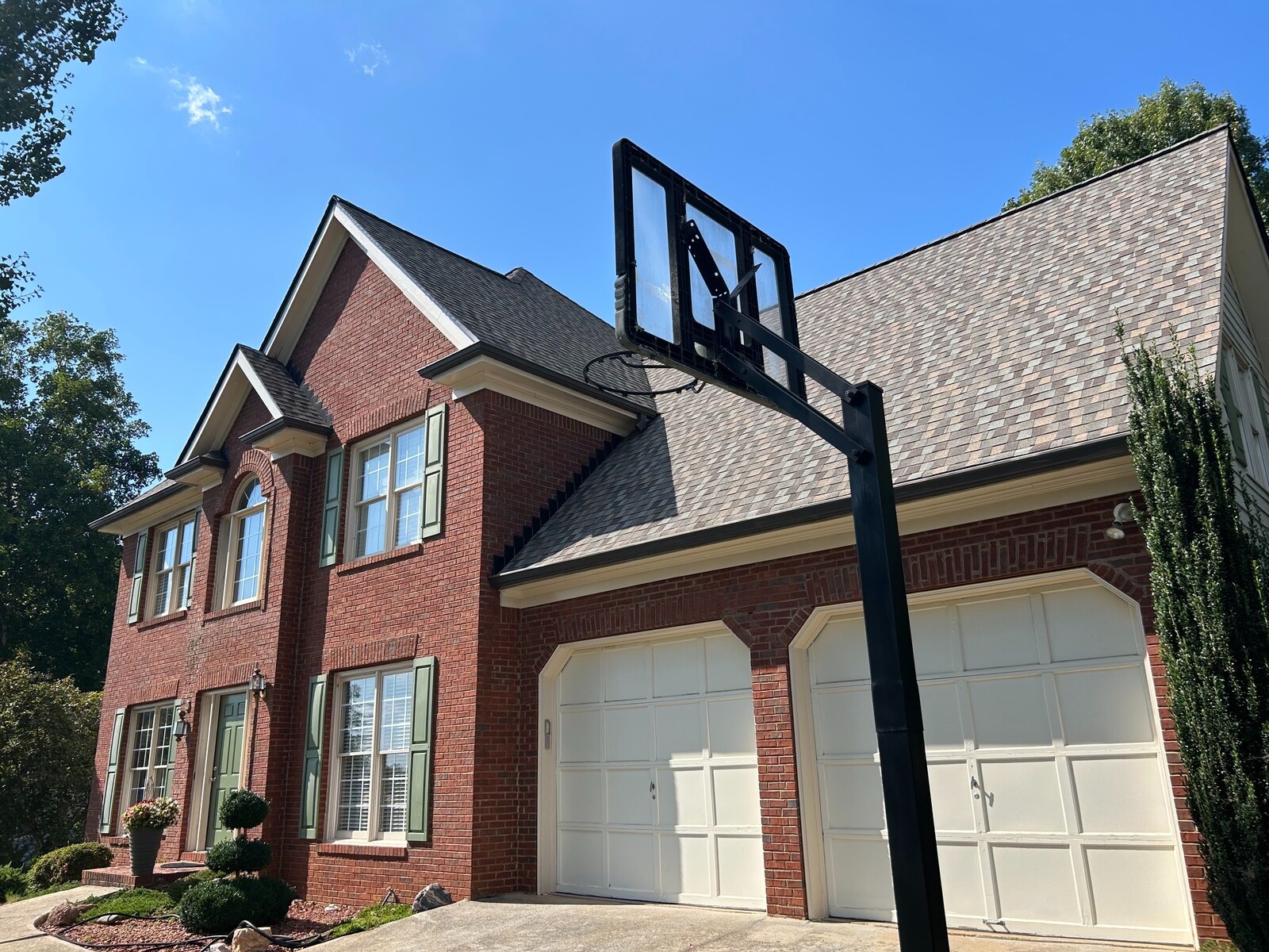 Completed architectural asphalt shingle roofing system on a two-story brick residence.