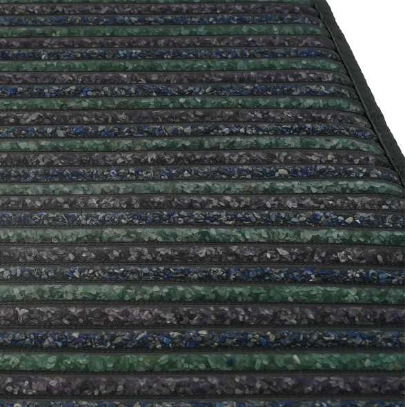 A close-up, angled view of a black, green, and blue striped mat with a textured surface. The mat is composed of horizontal bands, alternating between solid black and bands filled with small, irregular-shaped particles in shades of green and blue. The surface appears somewhat reflective. The edge of the mat is visible on the right side, with a black binding. The background is pure white, suggesting a studio or product shot.