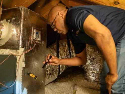 HVAC tech inspecting an attic furnace