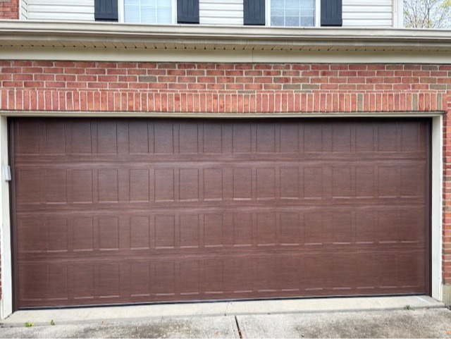 Modern residential sectional garage door with a wide flush-panel design and dark brown finish, installed by Highfield Door Sales in Oakwood, Ohio. This contemporary style delivers a sleek appearance, privacy, and long-lasting performance.
