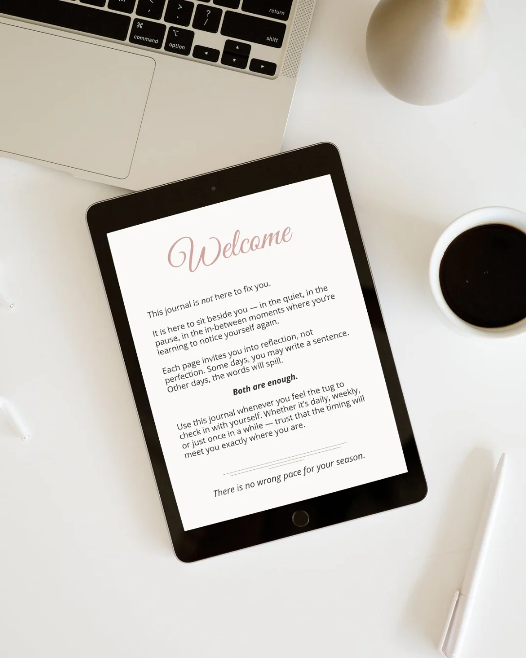 A tablet screen displaying the "Welcome" page of a digital journal titled "The Seasons of Me - The Season Check-In Journal". The journal features text related to self-reflection and personal growth. Beside the tablet is a laptop, a cup of dark coffee, and a white pen, suggesting a work or study environment.