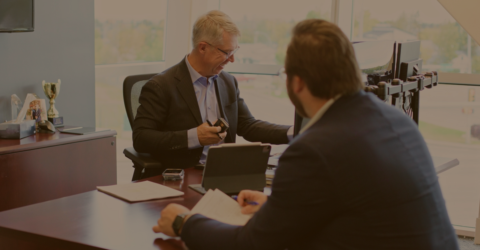 Kevin Chrenek and Tyson Beaupre in discussion in an office.
