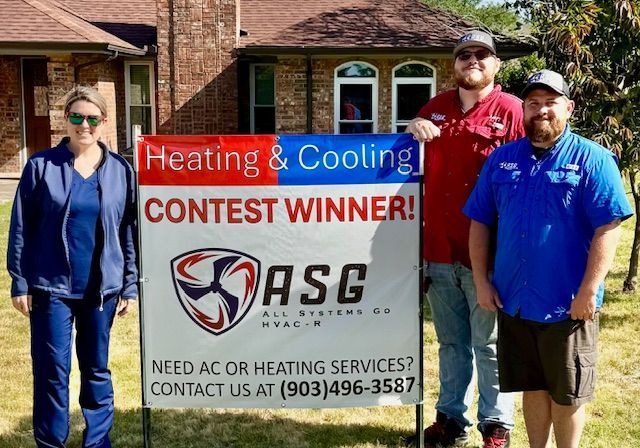 Three people&mdash;a woman in blue scrubs and two men in work shirts&mdash;stand outdoors, smiling beside a banner reading "Heating & Cooling Contest Winner!" and showing the ASG HVAC-R logo.