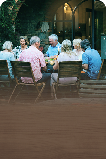 A multigenerational family gathered around a dining table in the backyard.