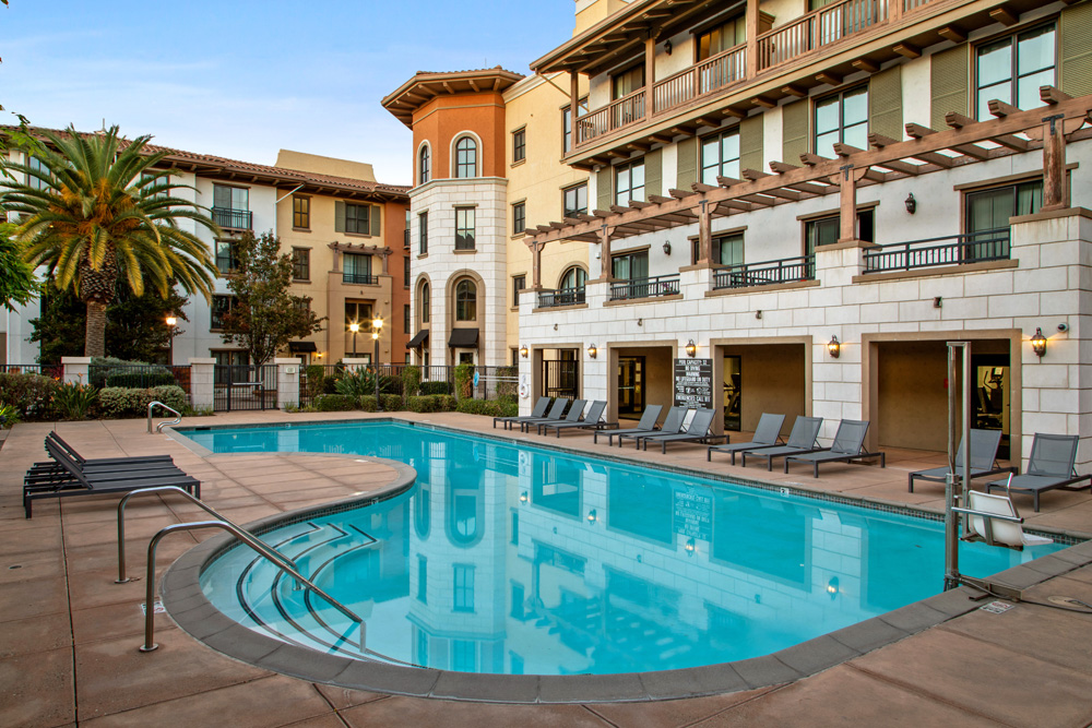 Resort-style pool with lounge seating and terrace with pergola.