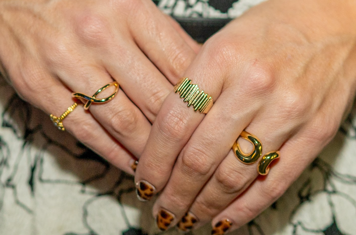 Gold-toned rings showcase sculptural curves, an open loop design, and a textured band, paired with leopard-print nail art. Discover unique statement rings at Eliana Curated in Old Town Alexandria, VA.