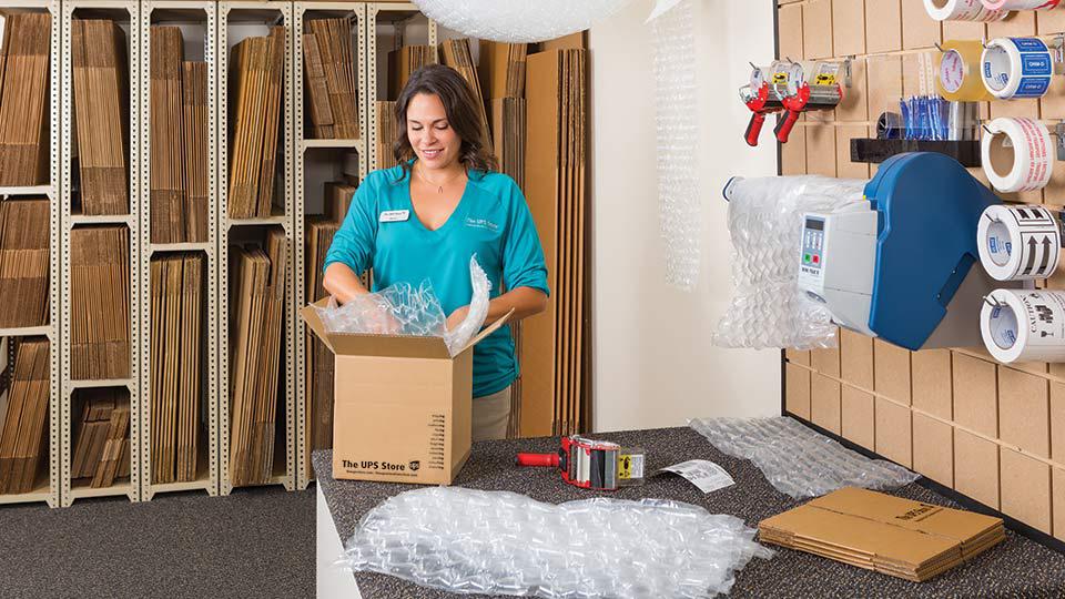 Un asociado de The UPS Store empaqueta una caja en la mesa de trabajo de The UPS Store.