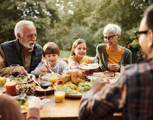 A multigenerational family having a meal outside.